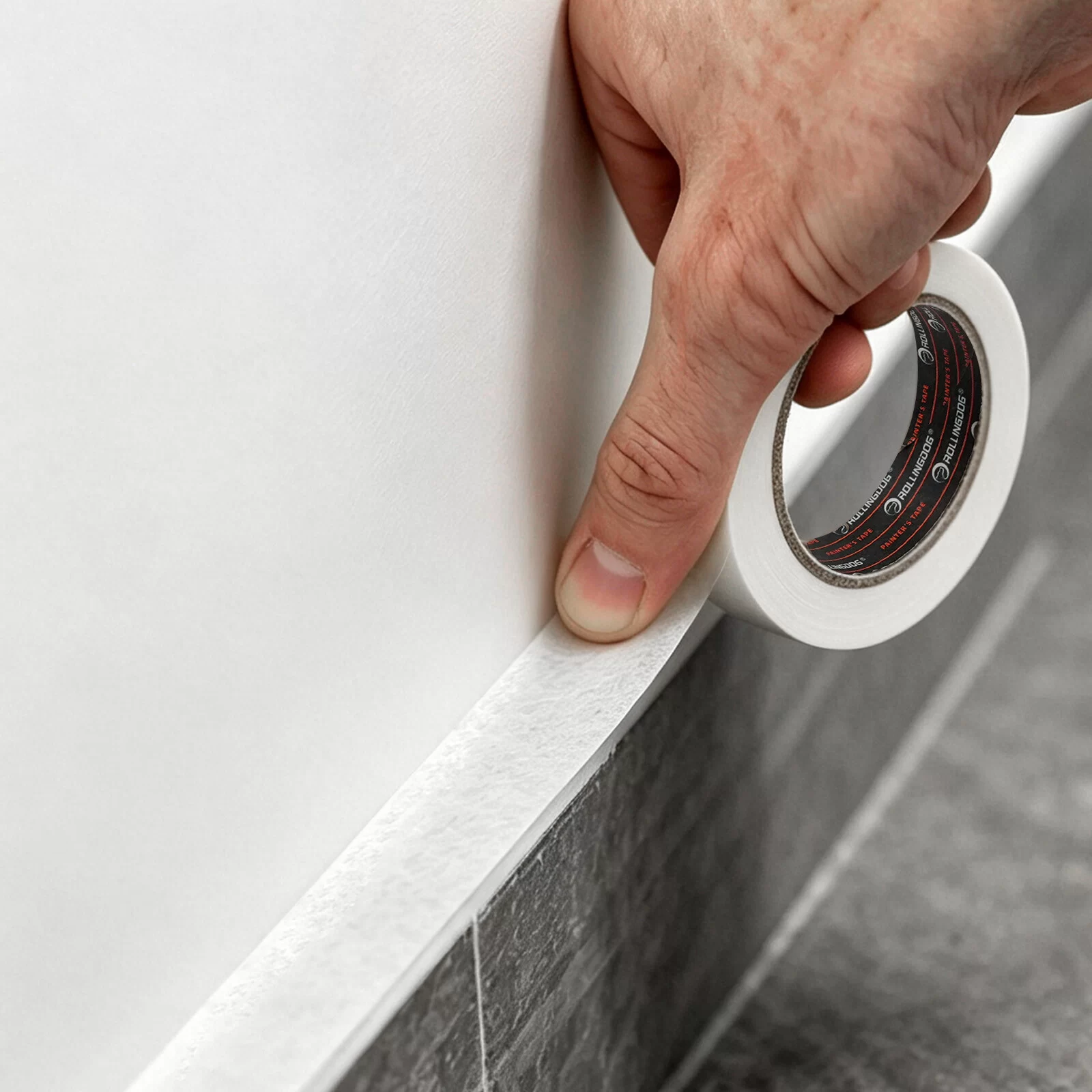 Applying painter's tape along baseboard and tile edge before painting